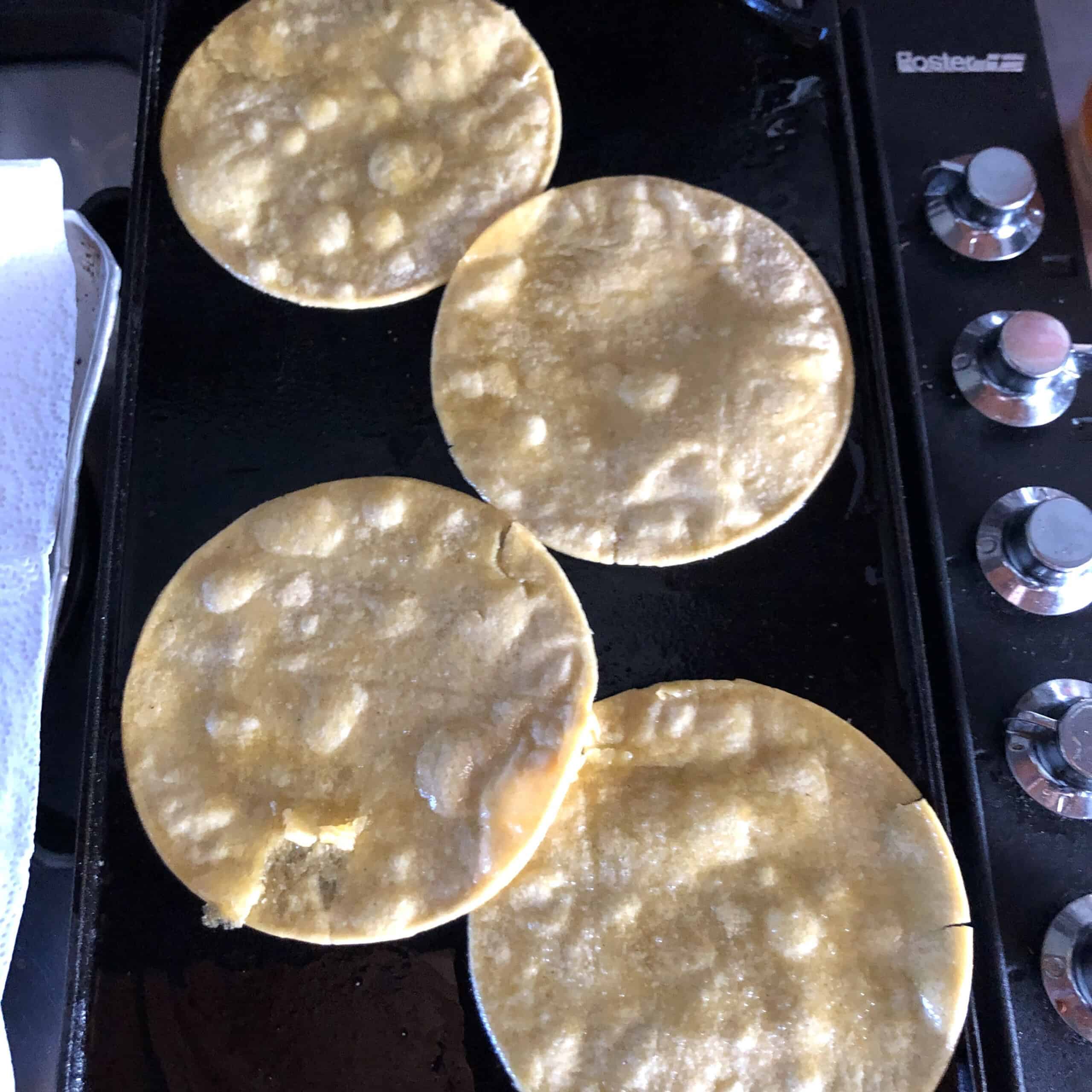 Lightly oiled corn tortillas warming on a Lodge cast iron griddle.
