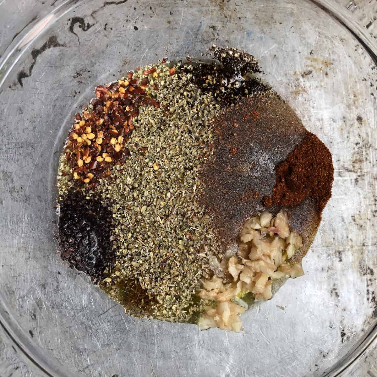 Gyro ingredients for a homemade Greek gyro recipe marinade in a bowl showing olive oil, white wine vinegar, honey, grated onion, garlic, and spices before mixing.
