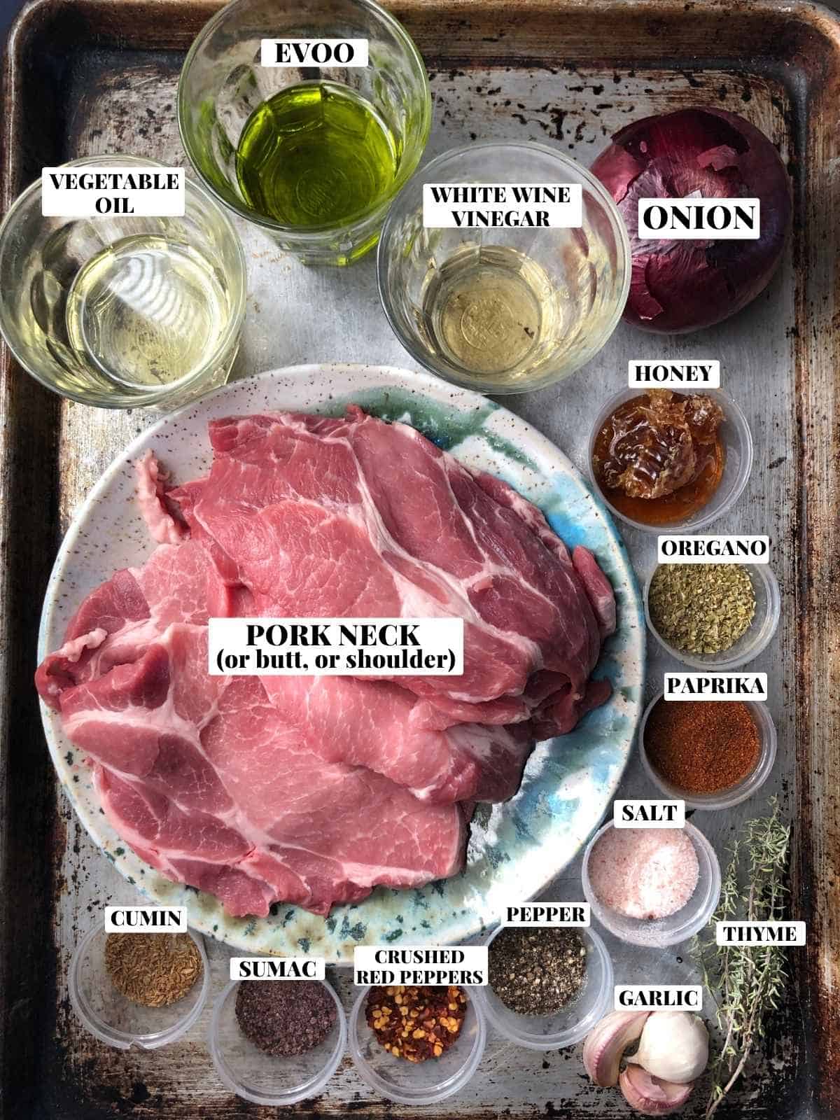 Gyro meat recipe ingredients on a cutting board including pork neck, gyro seasoning spices, olive oil, vegetable oil, onions, white wine vinegar, and fresh herbs.