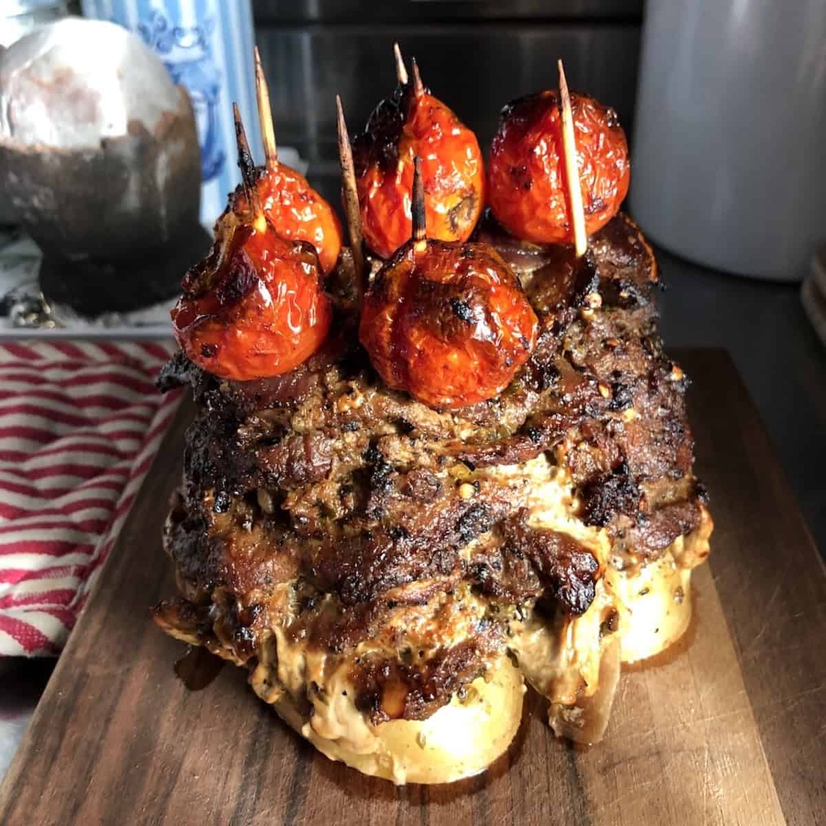 Crispy pork gyro meat tower resting on a cutting board before slicing.